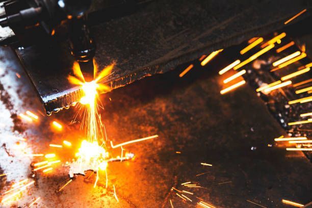 Laser cutting metal, sparks flying in a dark workshop.