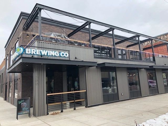 Brewing Co. building with rooftop seating, grey siding, and large windows. Sign reads 