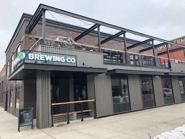 Brewing company building with an outdoor patio, gray siding, and a sign that reads