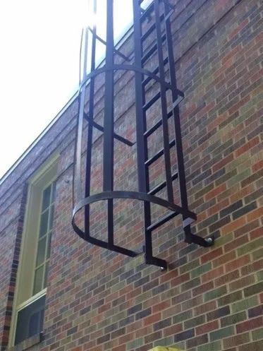 Exterior metal ladder with cage attached to a brick building.
