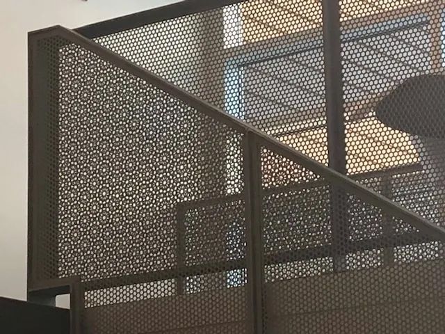 Metal stair railing with decorative geometric pattern.