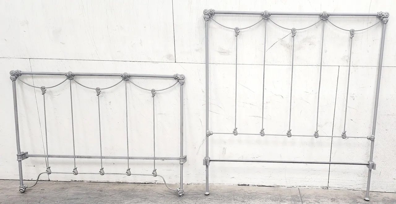 Two metal bed frames, one smaller, one larger, against a white wall.