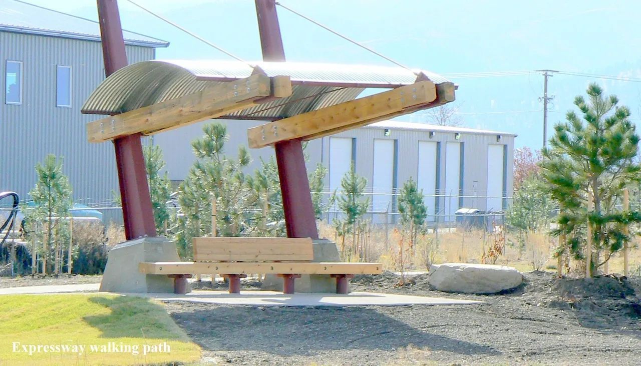 Sheltered bench in park with red support beams, wooden beams, and metal roof.