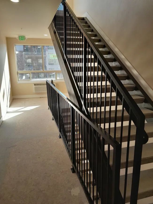 Staircase with black metal railings. Beige walls, window on the left.