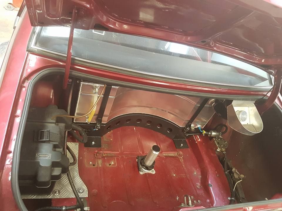 The trunk of a red car with the hood open.