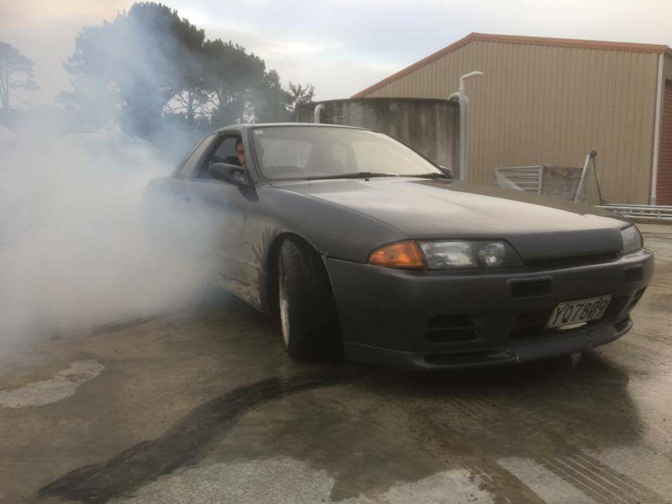 A car with smoke coming out of it is parked in front of a building.