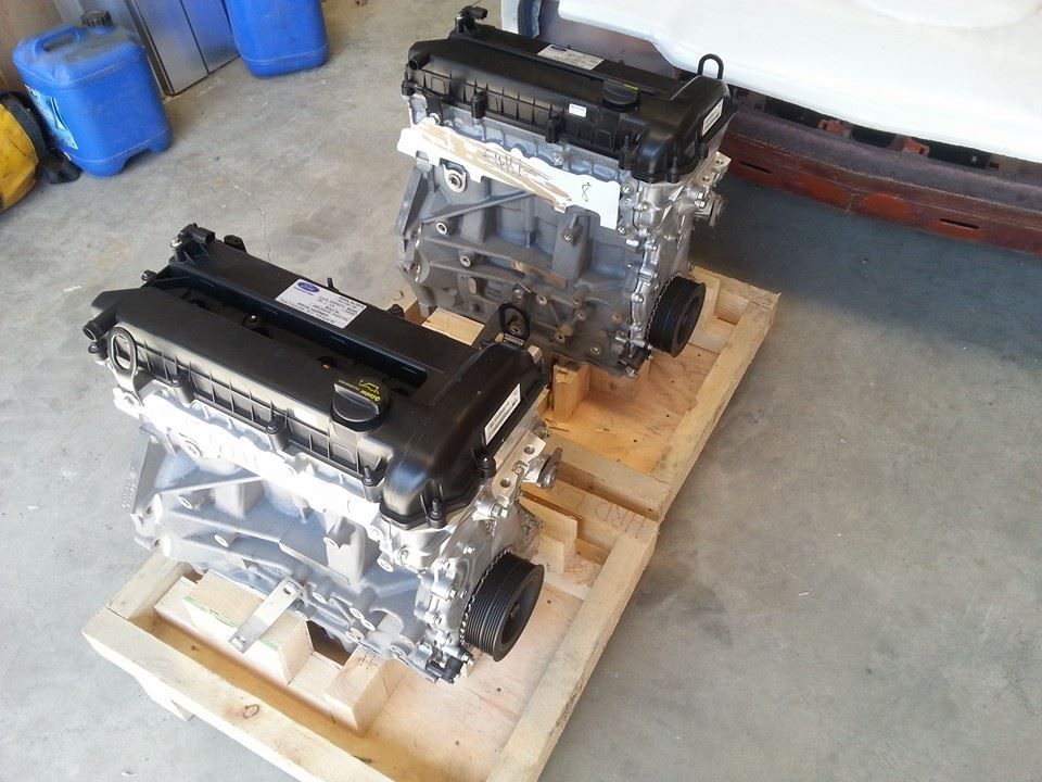 Two engines are sitting on wooden crates in a garage.
