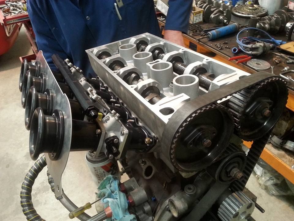 A man in a blue shirt is working on a car engine.