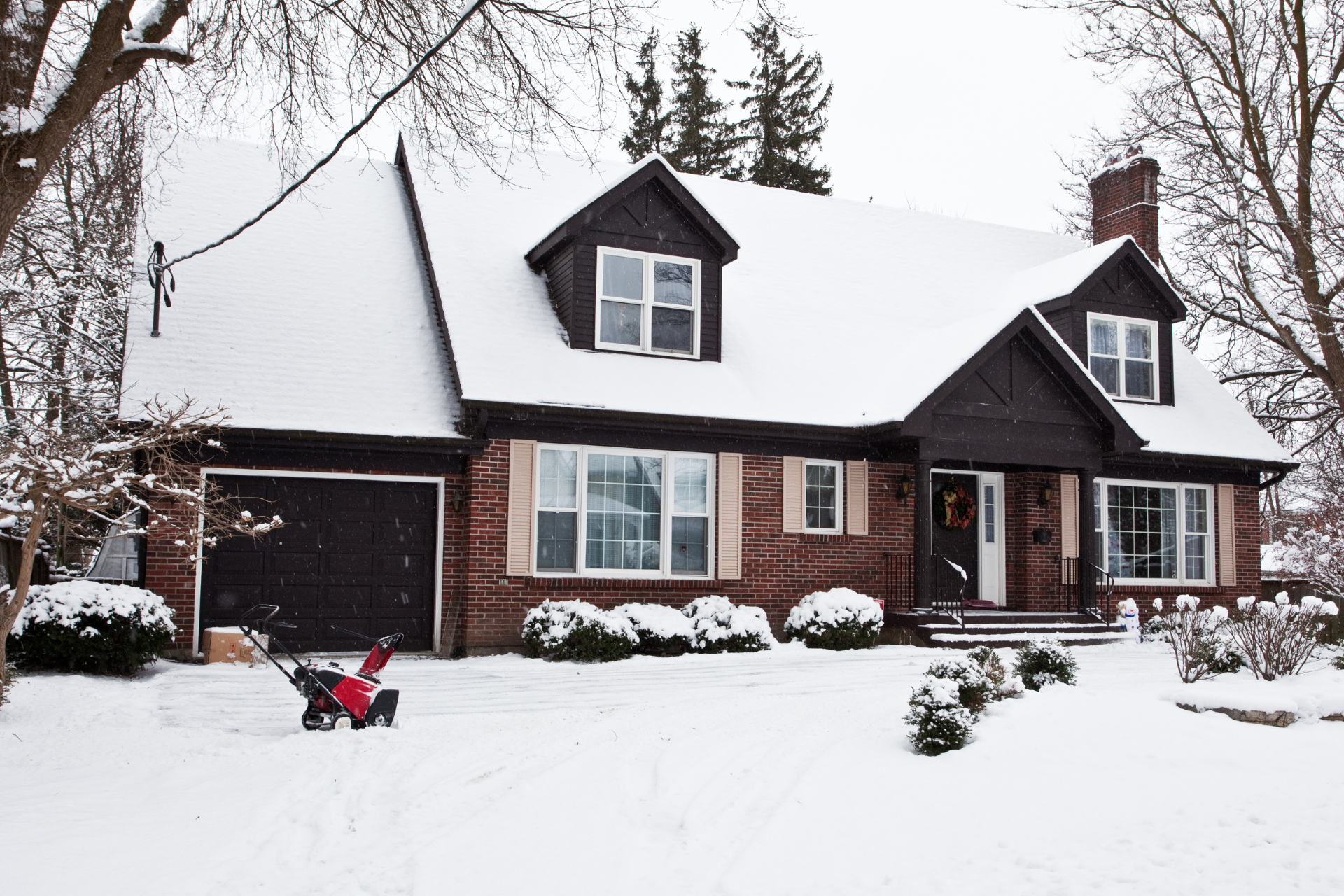 A house with a snow blower in front of it