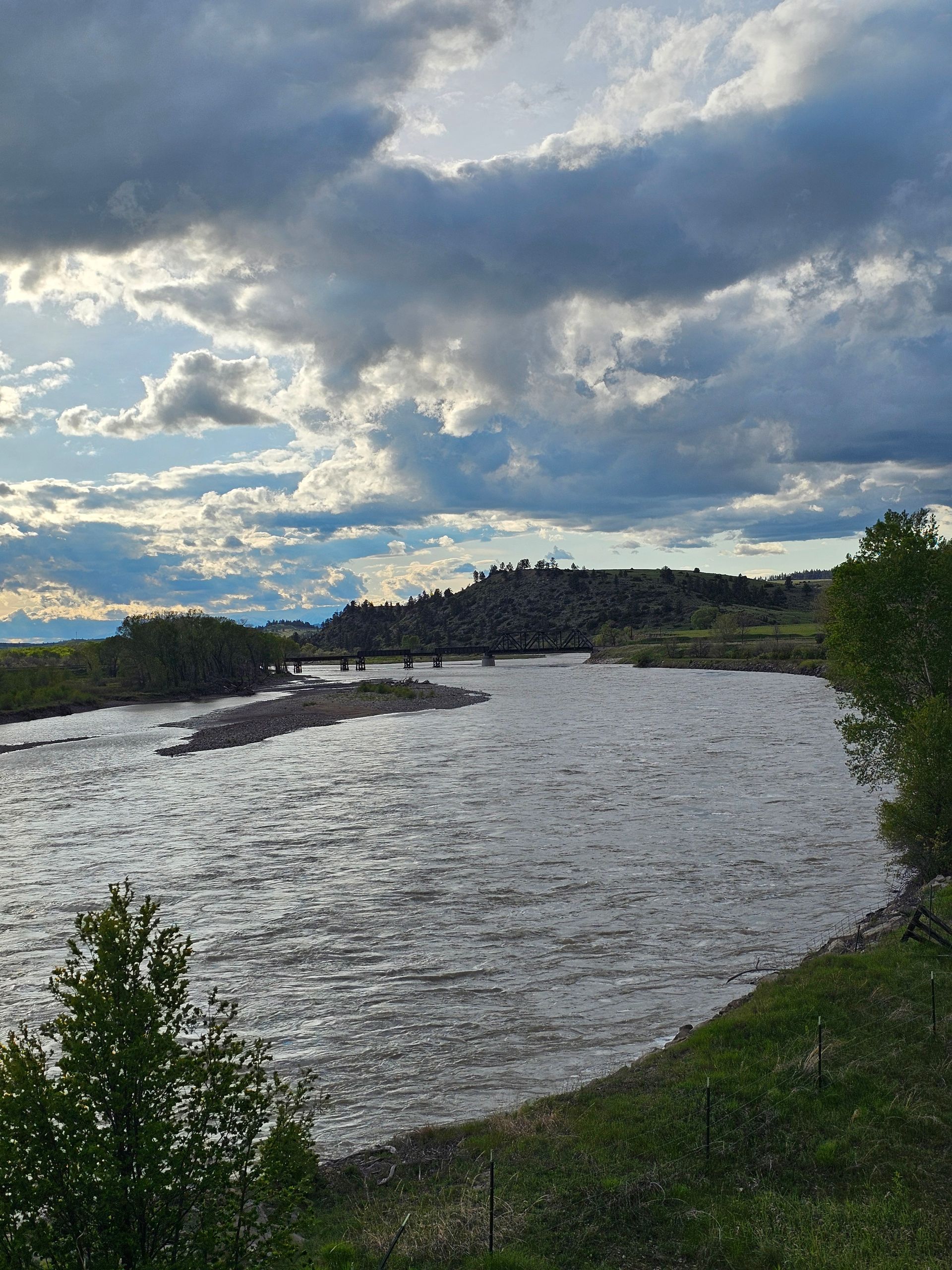A river with a bridge in the distance and a cloudy sky.