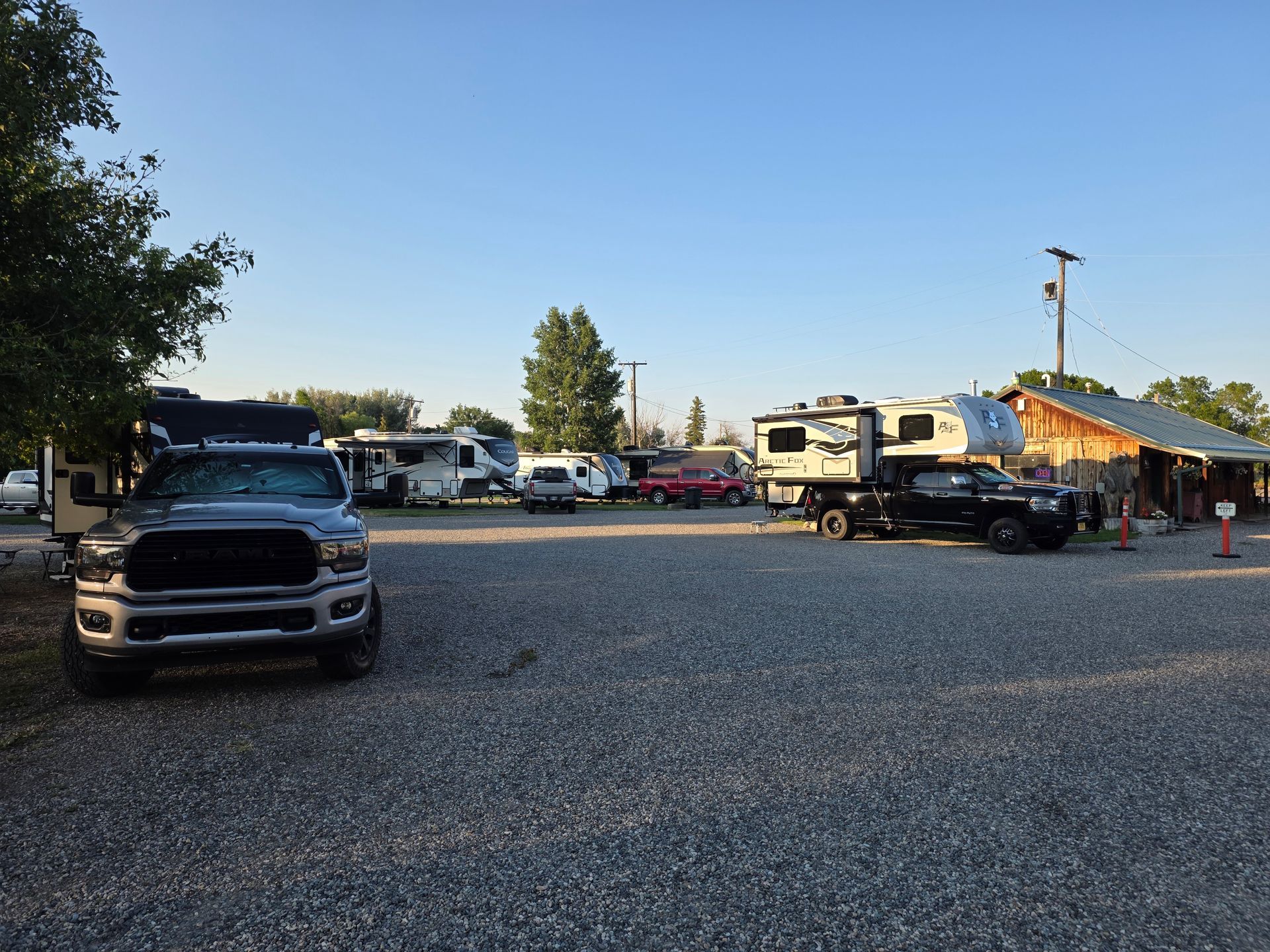 Campground with RVs and trucks parked on gravel under a clear sky.