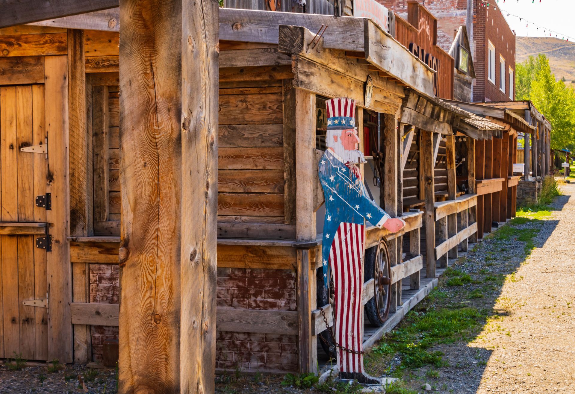 Uncle Sam cutout standing on a porch in front of weathered wooden buildings.