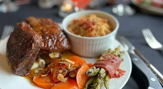 A plate of food with meat , carrots , rice and asparagus on a table.