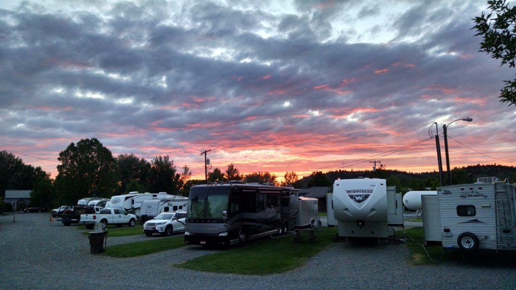 A lot of rvs are parked in a parking lot at sunset.