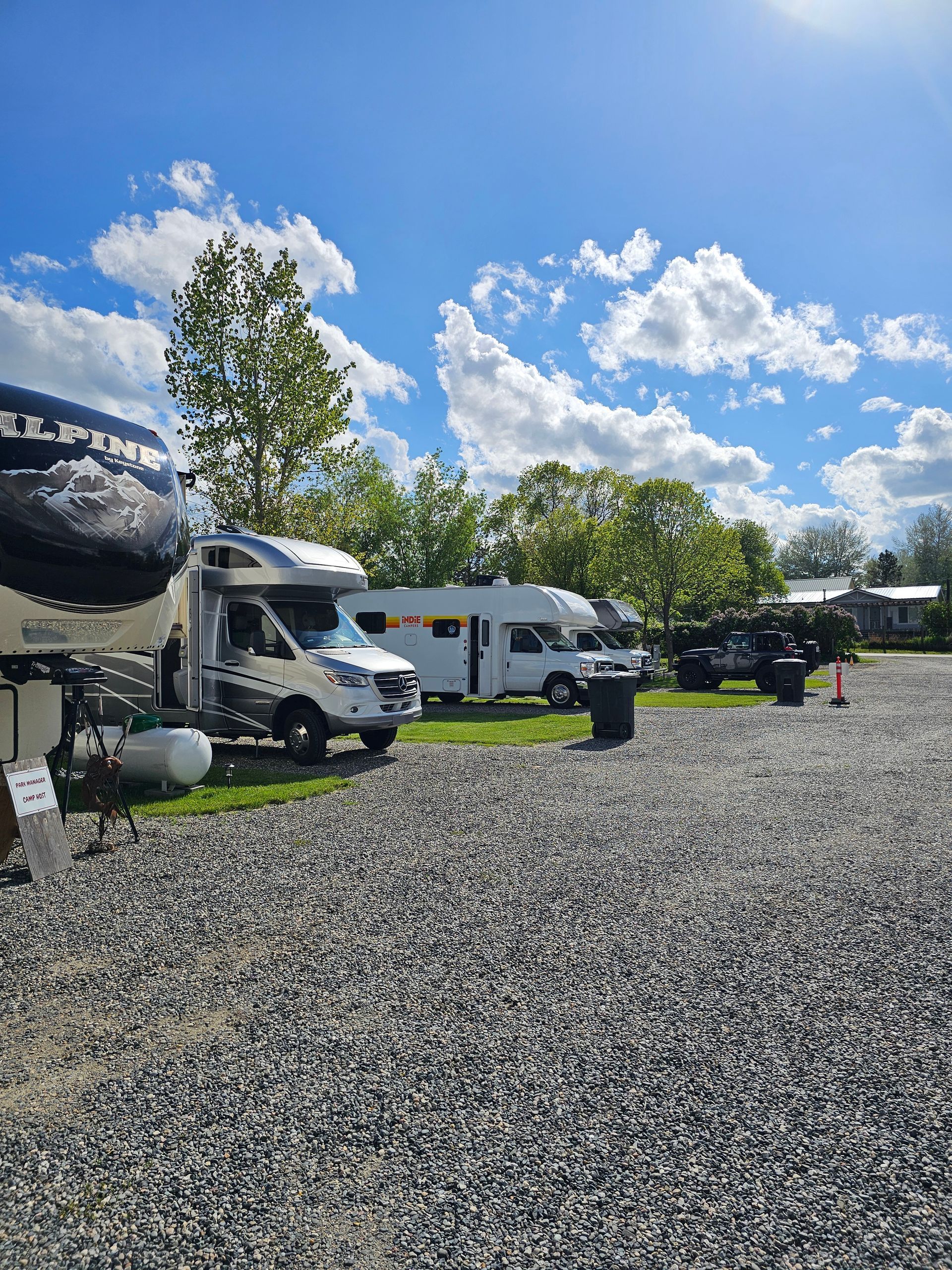 A row of rvs parked in a gravel lot.