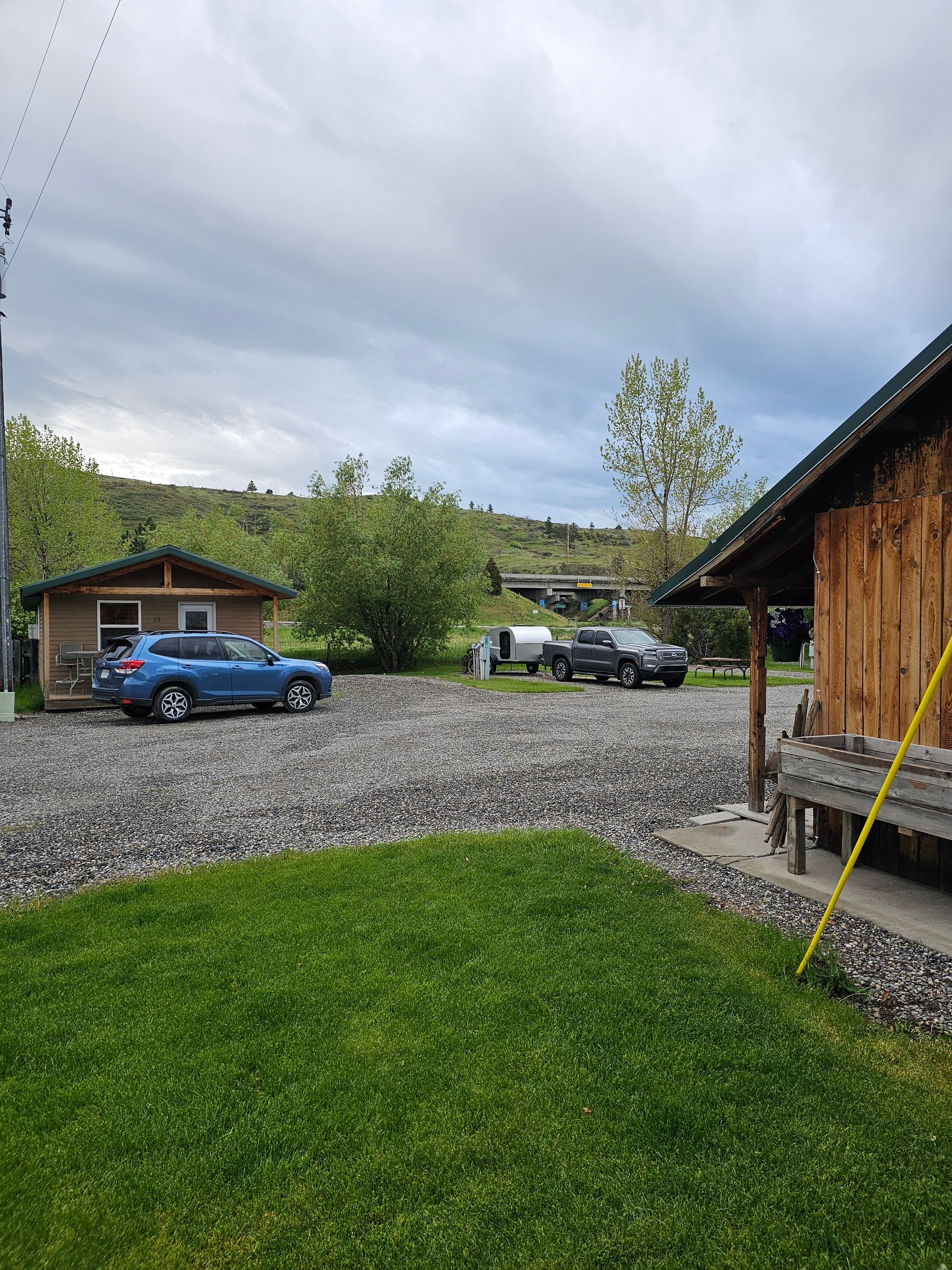 A blue suv is parked in a gravel driveway next to a small house.