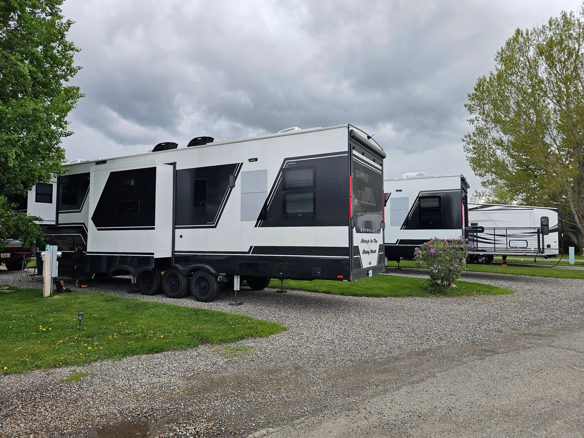 A white and black rv is parked in a gravel lot.