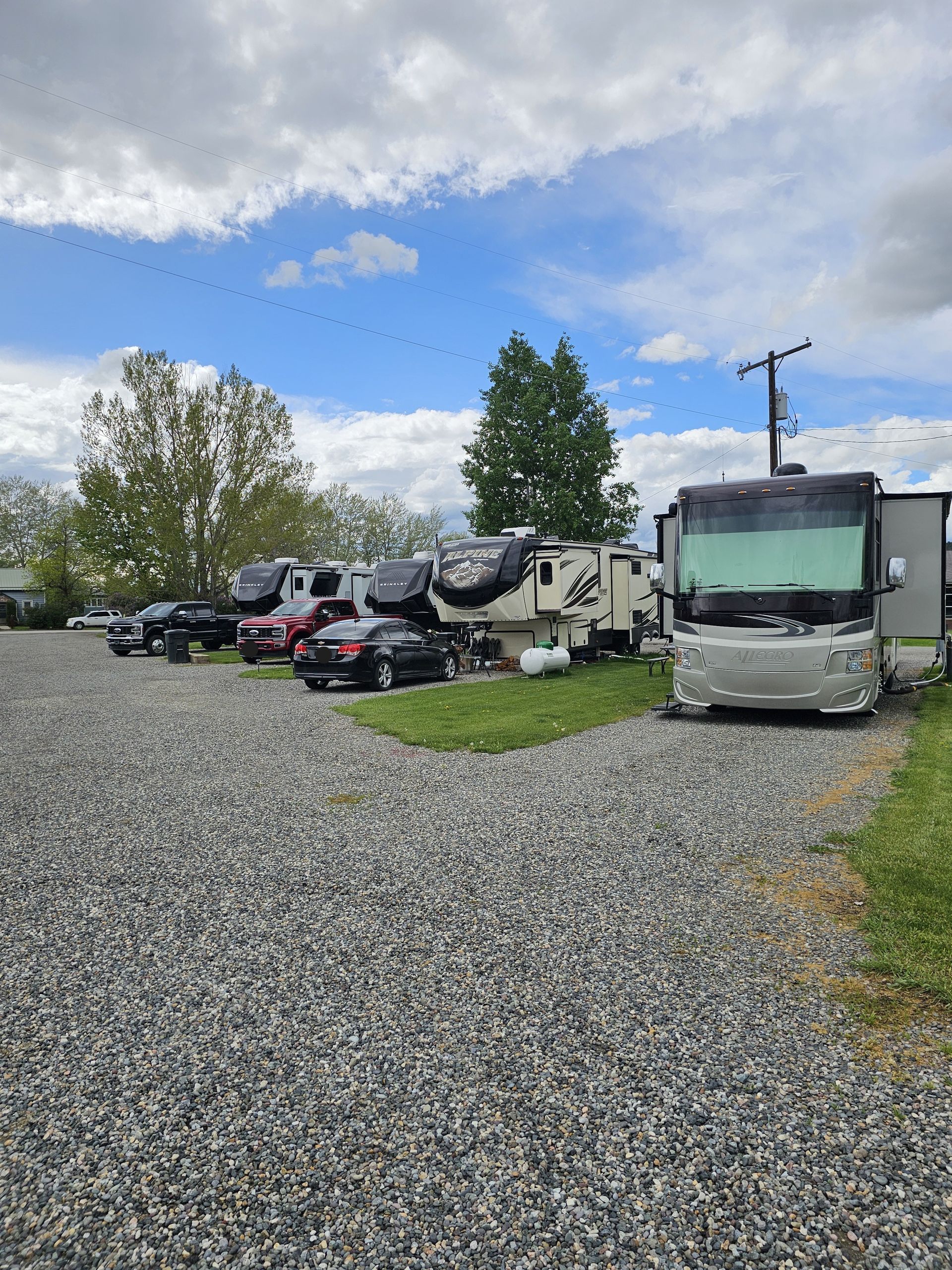 A row of rvs are parked in a gravel lot.