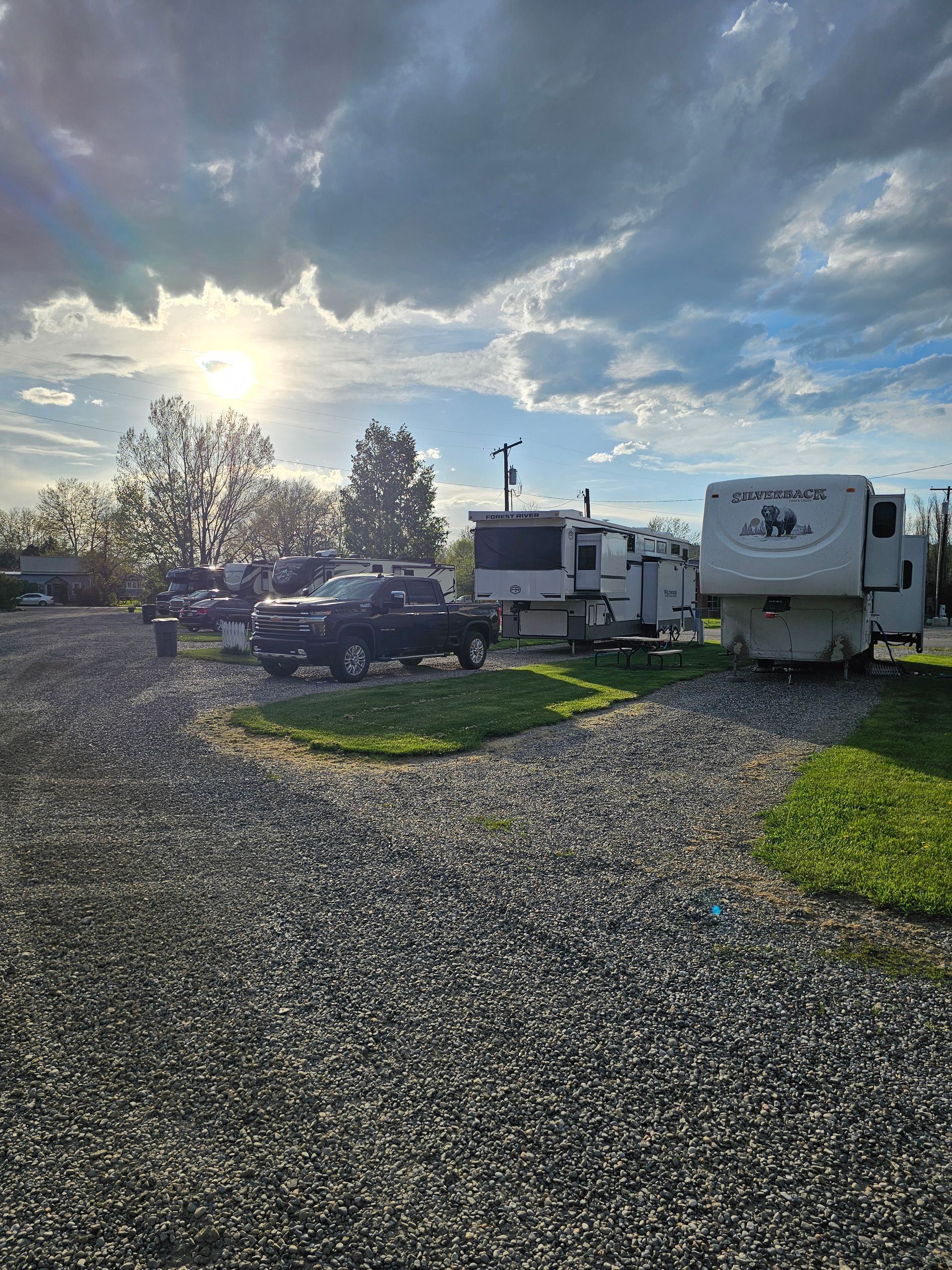 A lot of rvs are parked in a gravel lot.