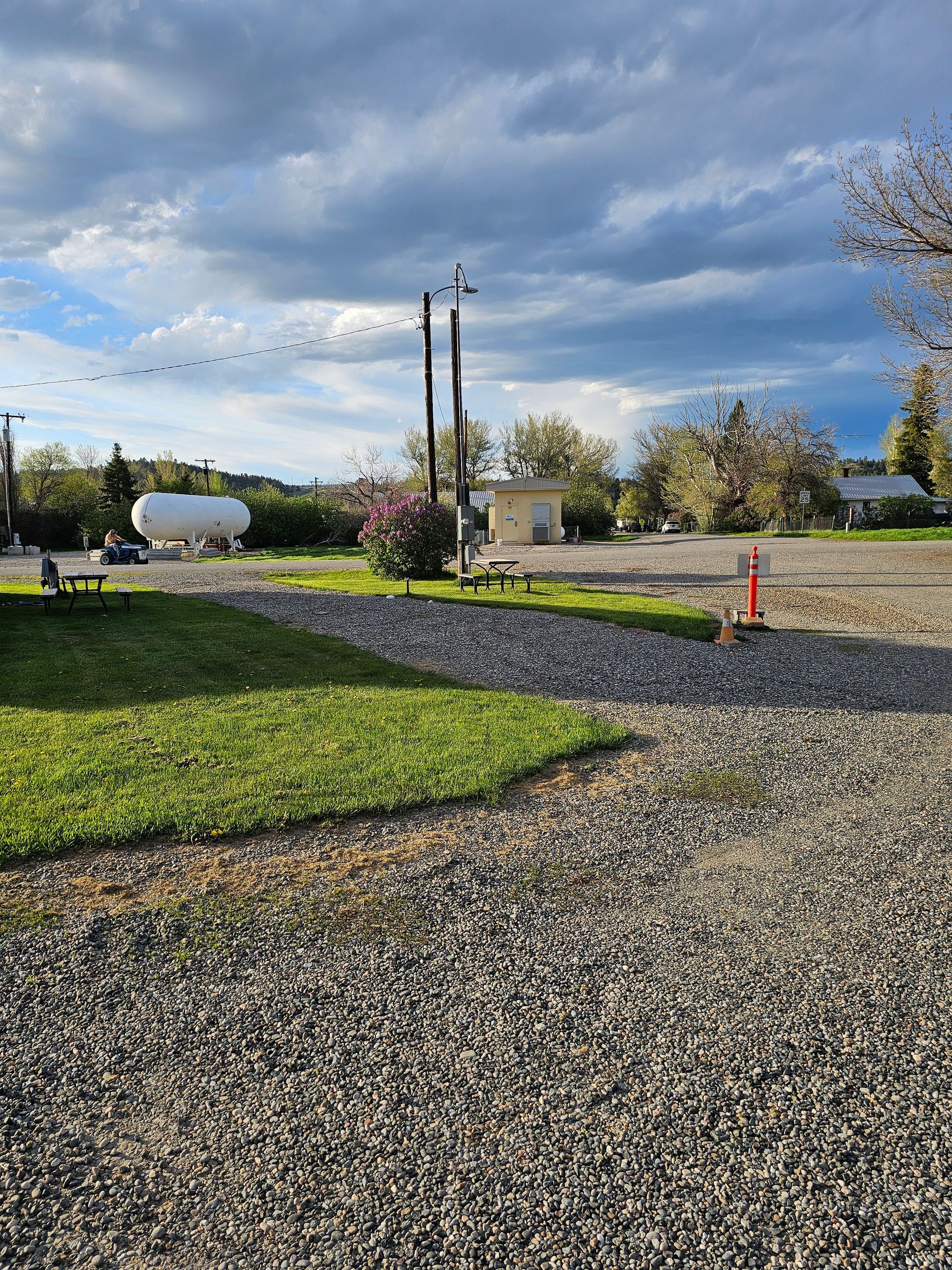 A gravel road with a propane tank in the background.
