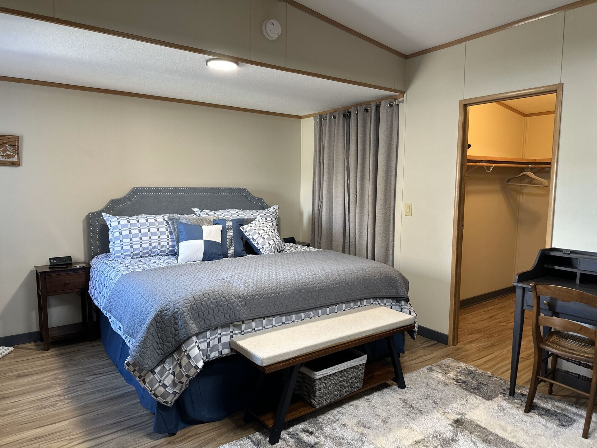 A bedroom with a king size bed , desk , chair and closet.