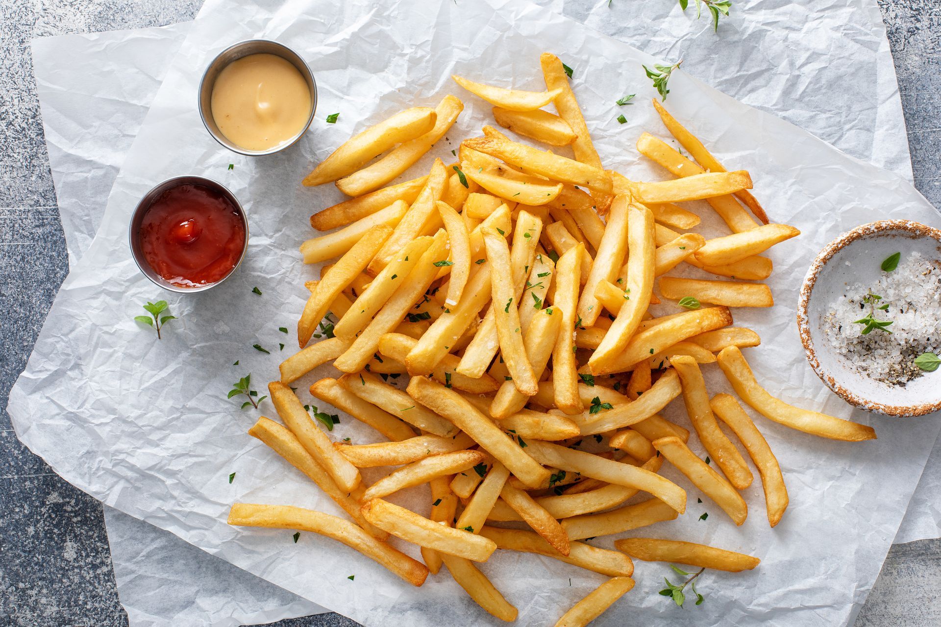 A pile of french fries with ketchup and cheese on a piece of paper.