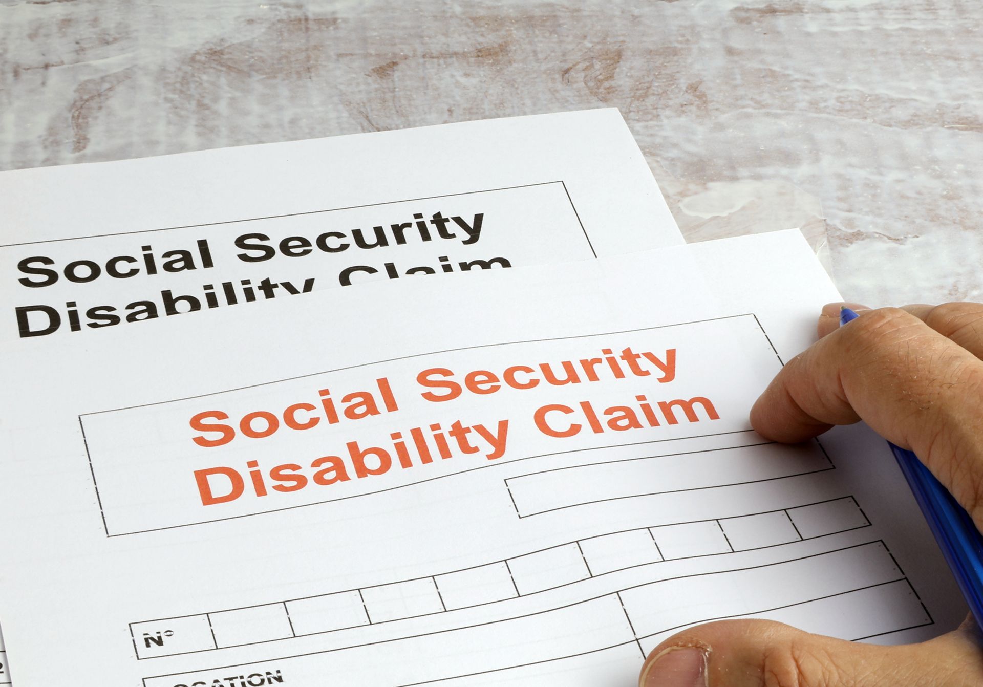 Close-up of official forms for social security disability assistance being reviewed and signed.