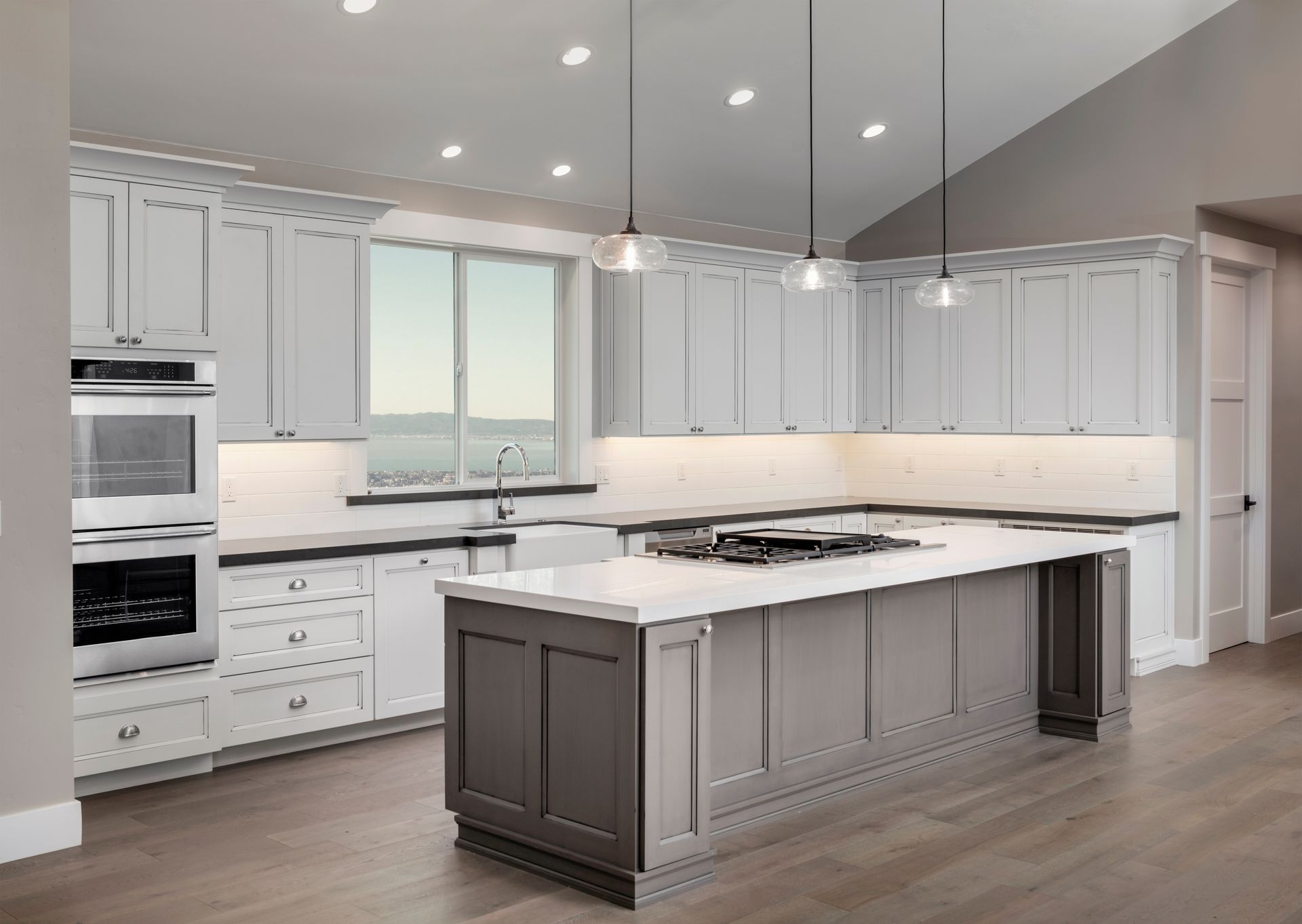 Modern kitchen with white cabinets, gray island, and stainless steel appliances.