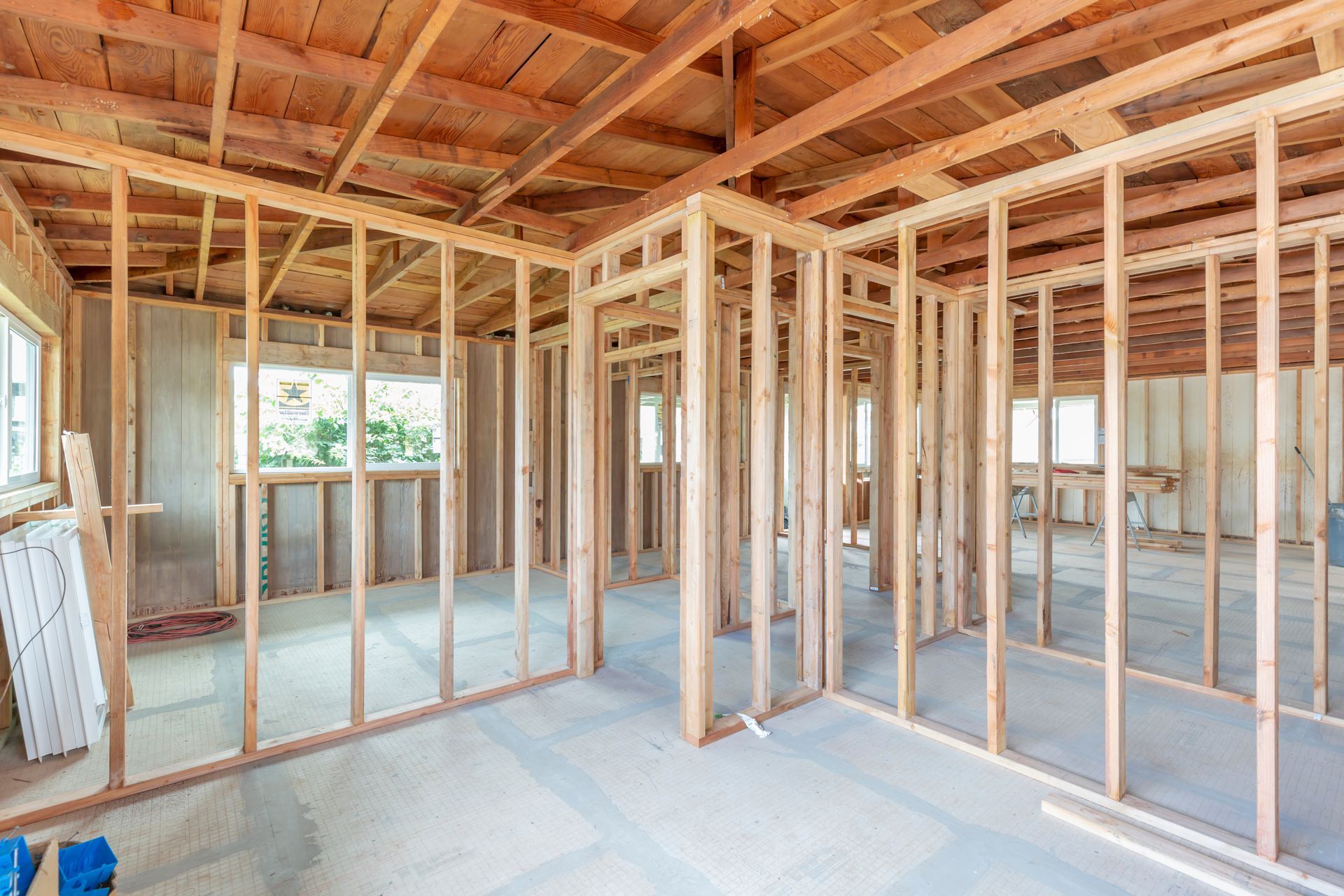 Interior of a building under construction, showing wooden wall frames and exposed ceiling beams.