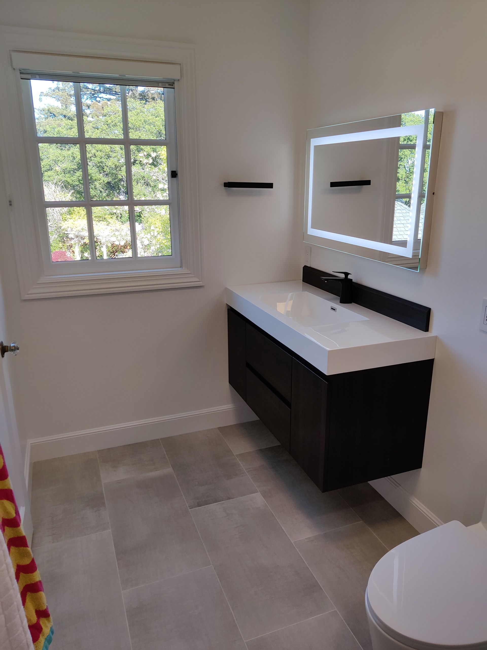 Bathroom with gray cabinets, white countertop, and a wooden door.