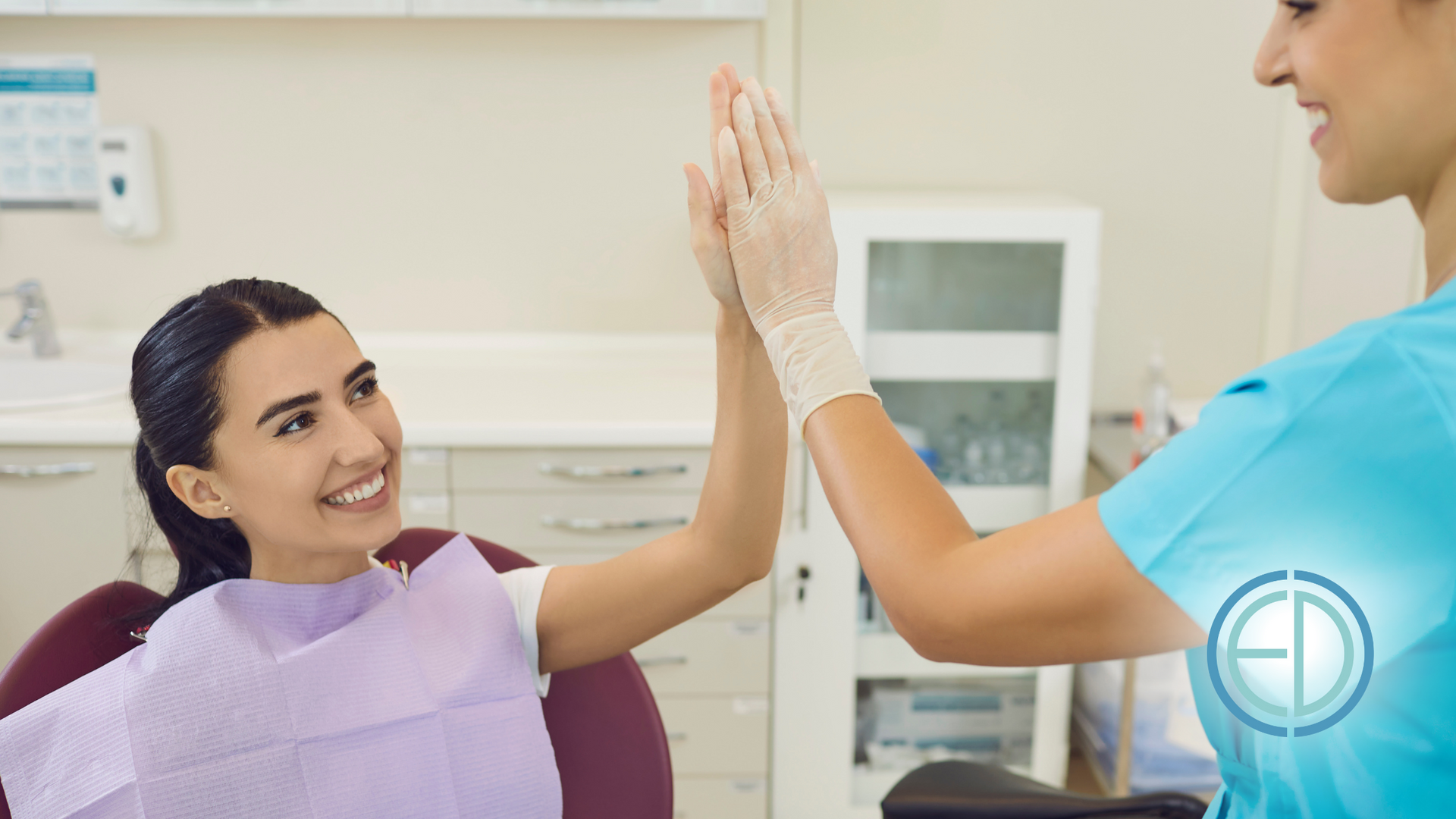 A dentist and a patient are giving each other a high five in a dental office.