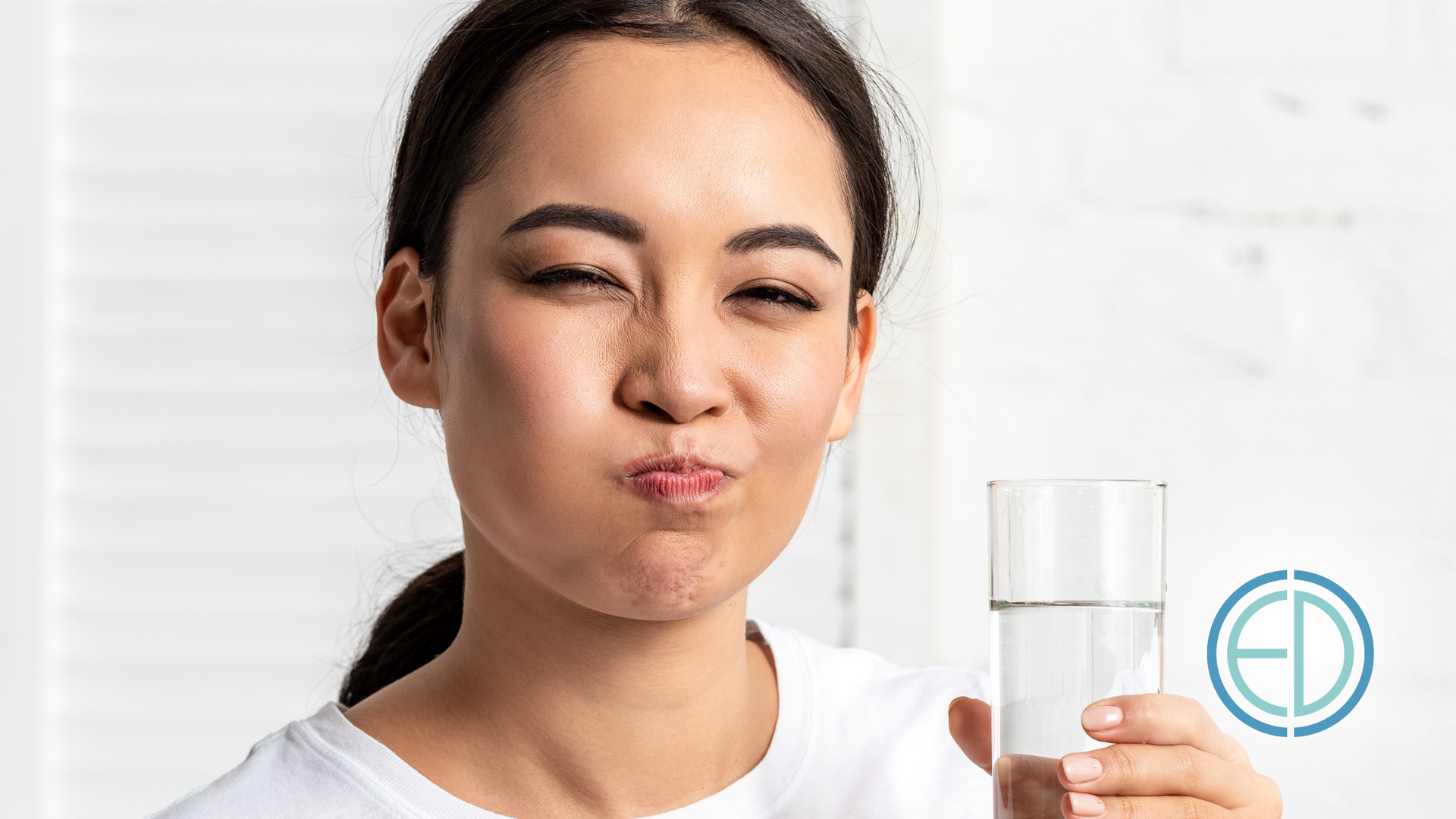 A woman is holding a glass of water in her hand.