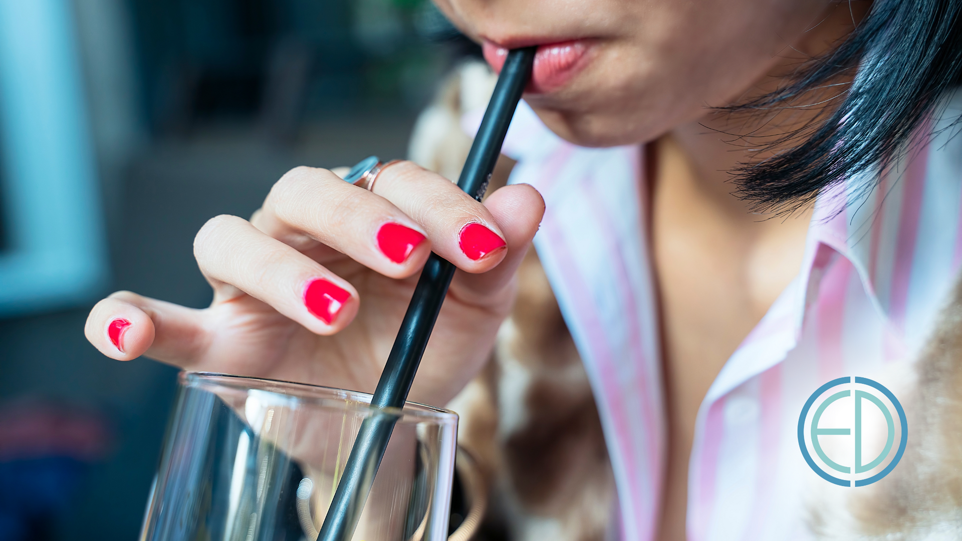 A woman is drinking through a straw from a glass.