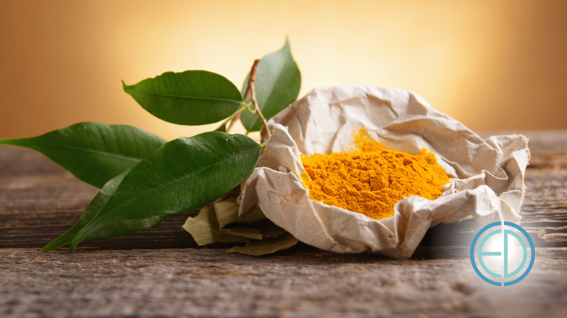 A pile of turmeric powder with leaves on a wooden table.