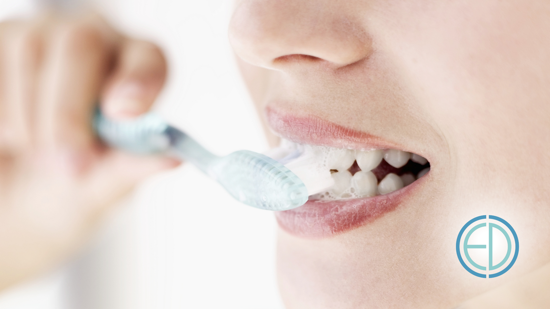 Person brushing teeth with a blue toothbrush; close-up of mouth and teeth.