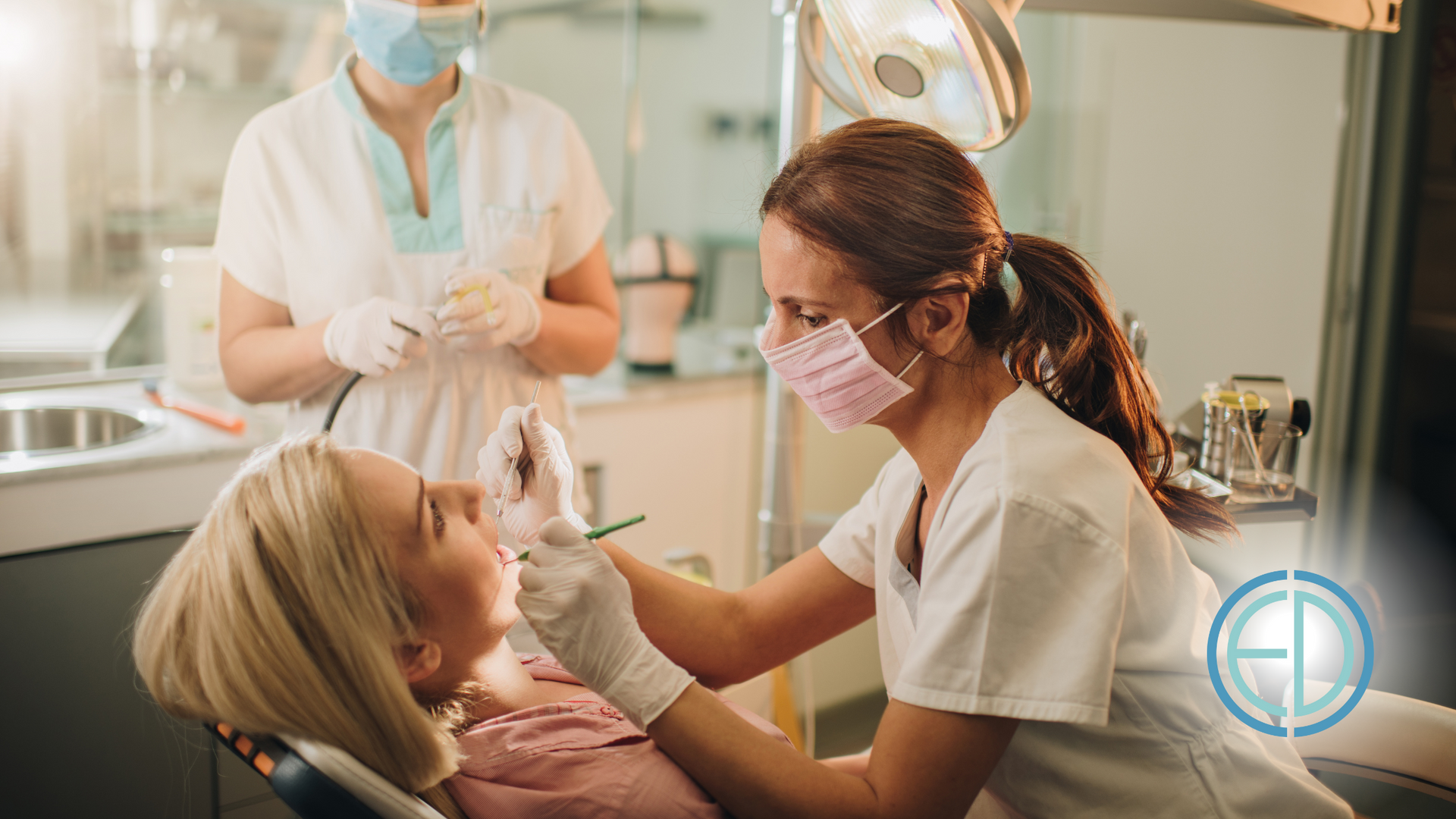 A woman is sitting in a dental chair while a dentist examines her teeth.