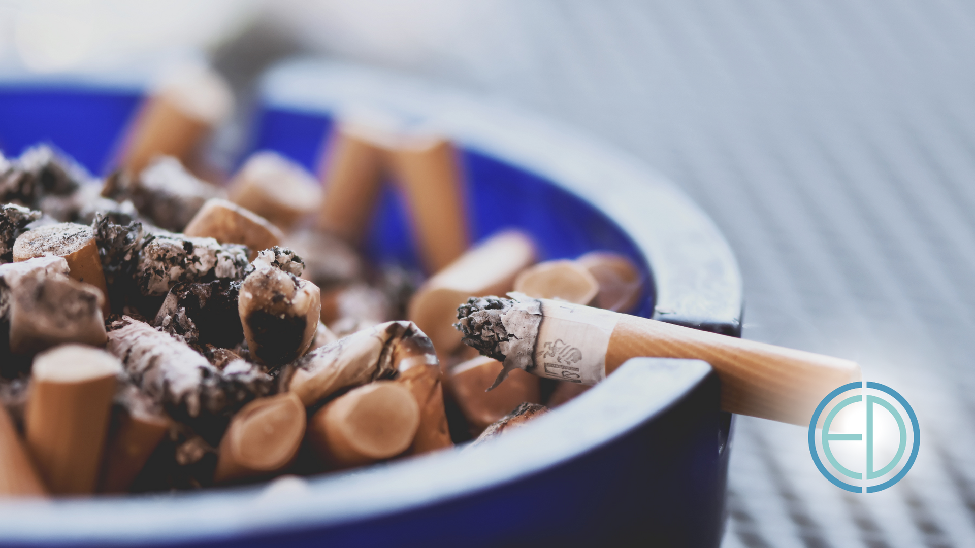 A blue ashtray filled with cigarettes on a table.