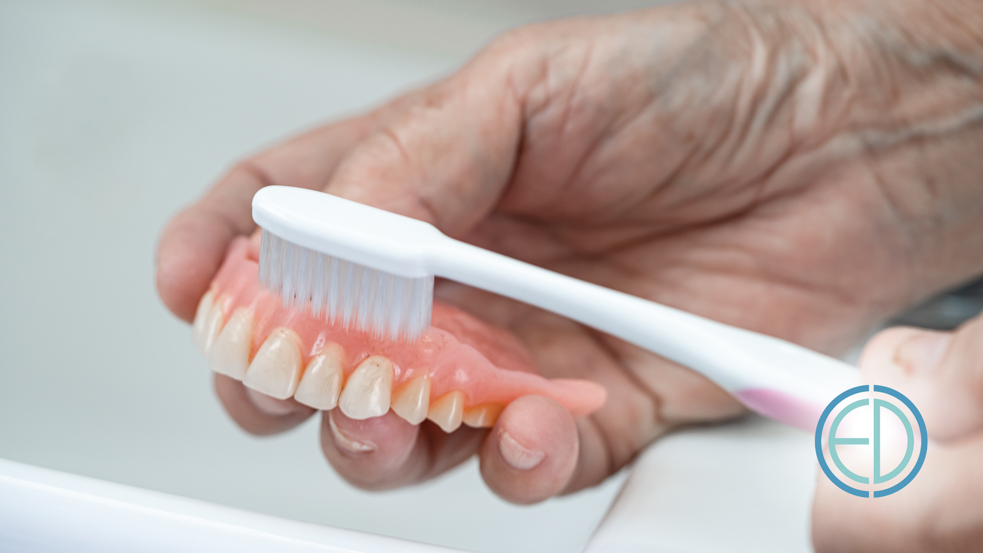 Person brushing dentures with a toothbrush in a sink.