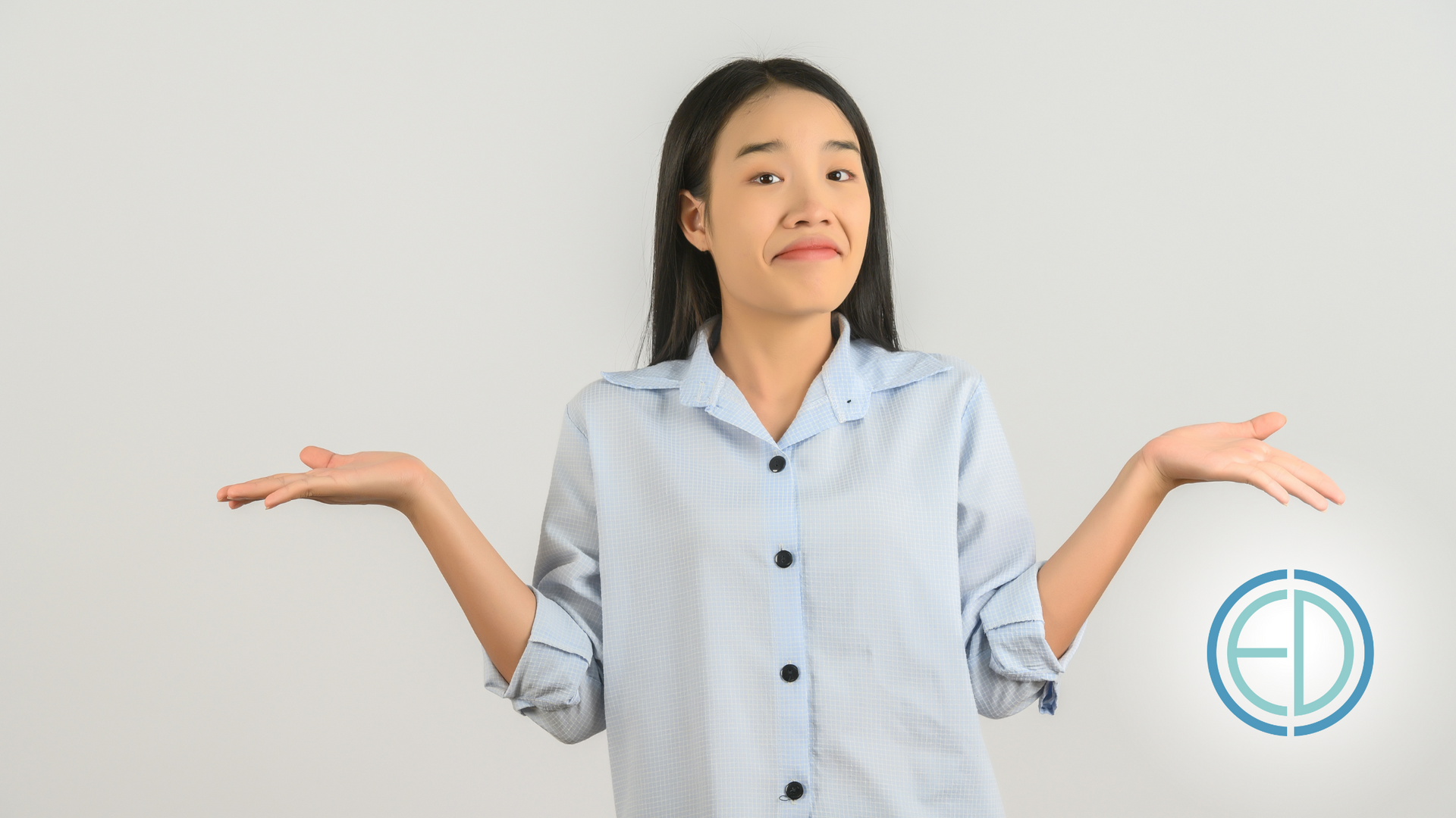 A woman in a blue shirt is shrugging her shoulders.