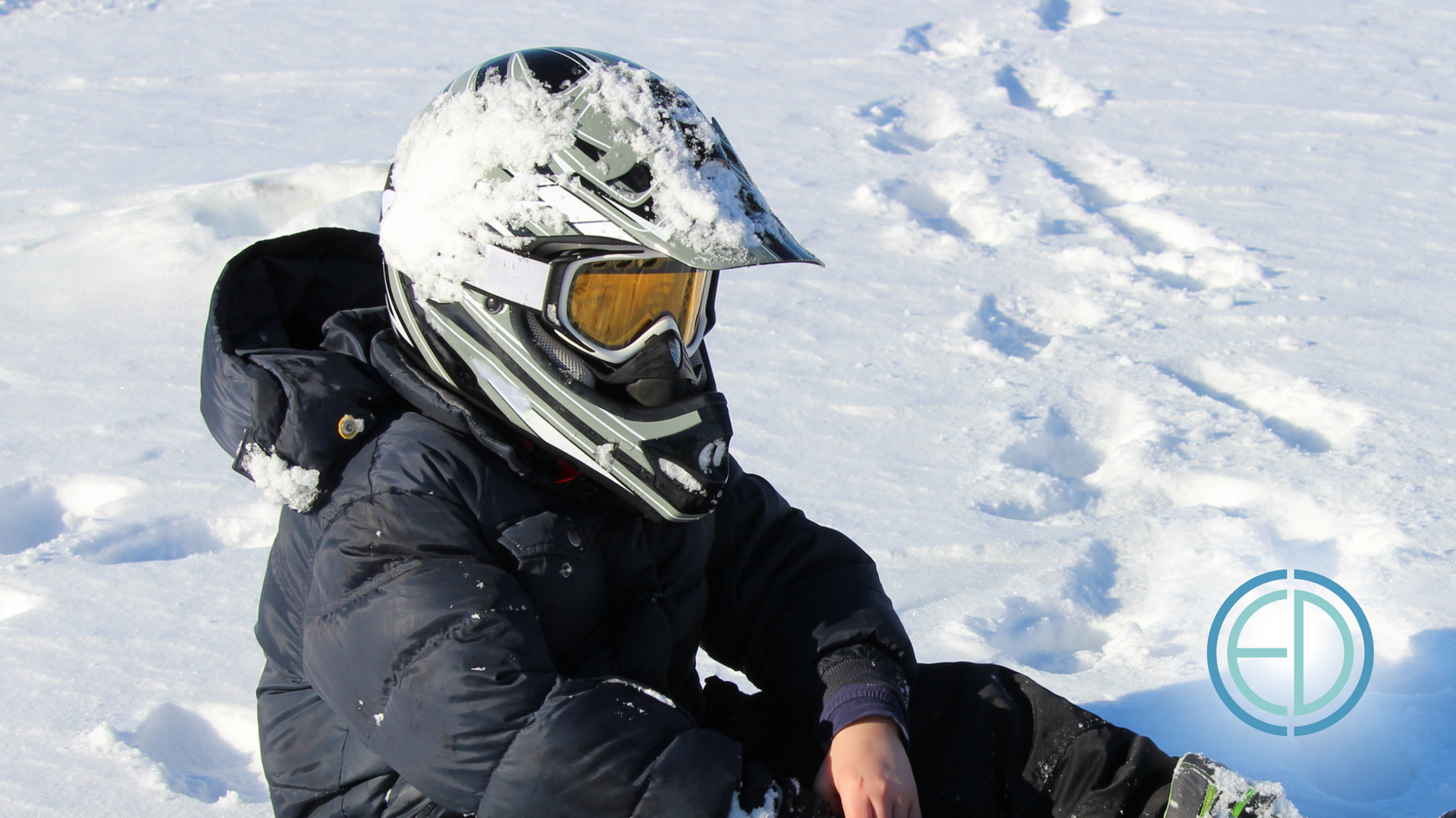 A person wearing a helmet and goggles is sitting in the snow