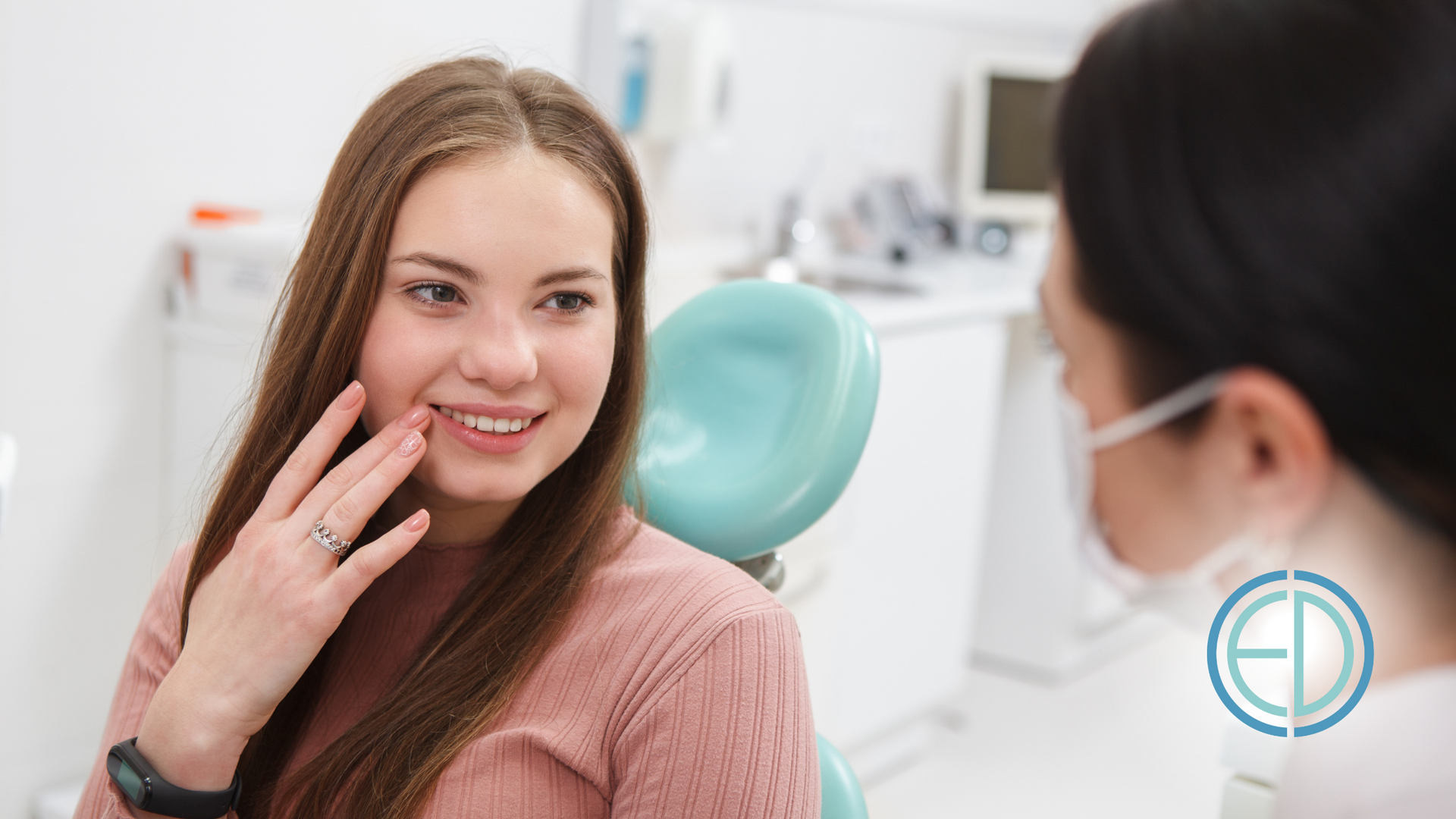Woman in dental chair smiling at dentist, holding her hand near her mouth in a bright, clean office.