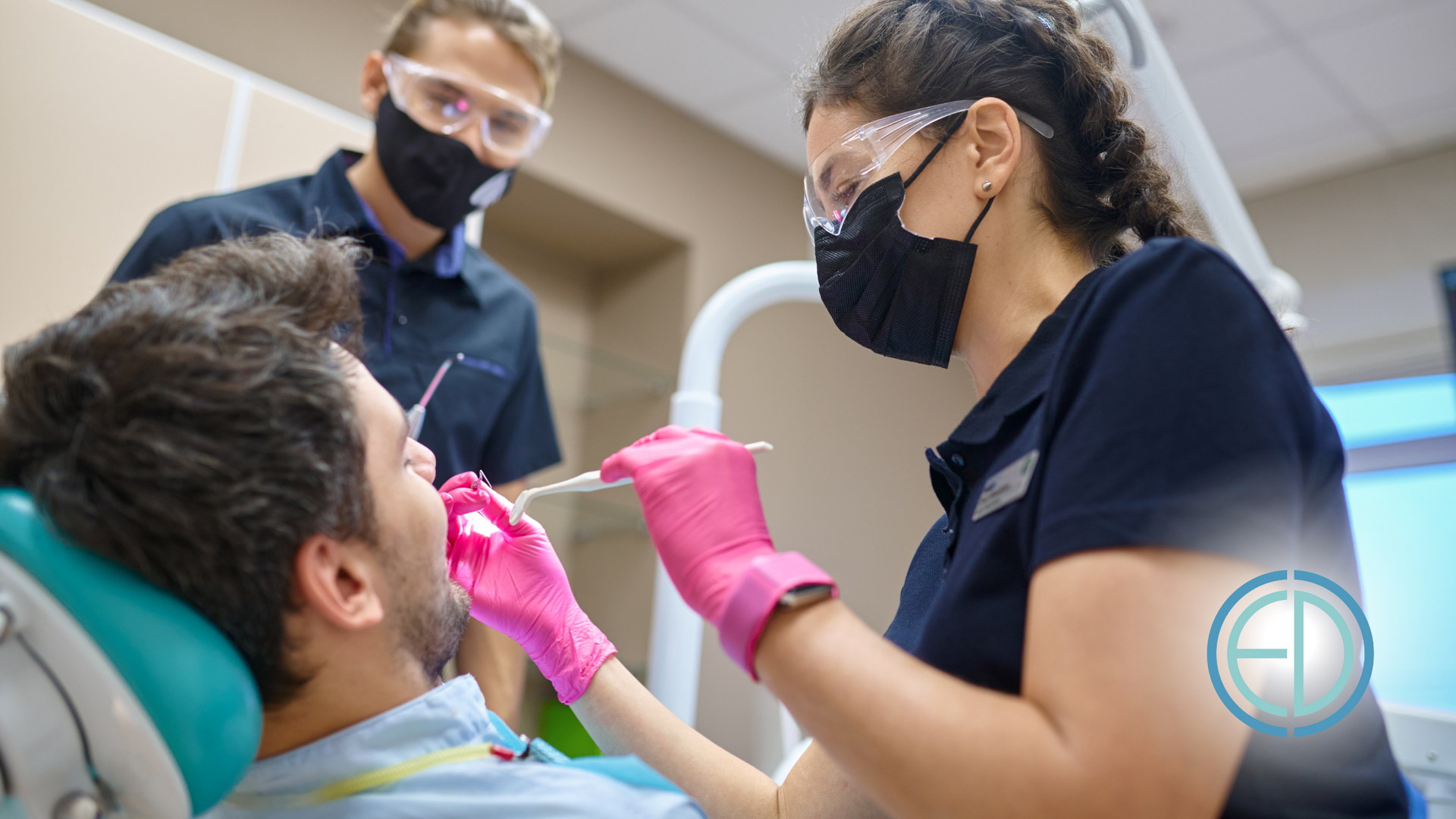 A man is sitting in a dental chair while a dentist examines his teeth.