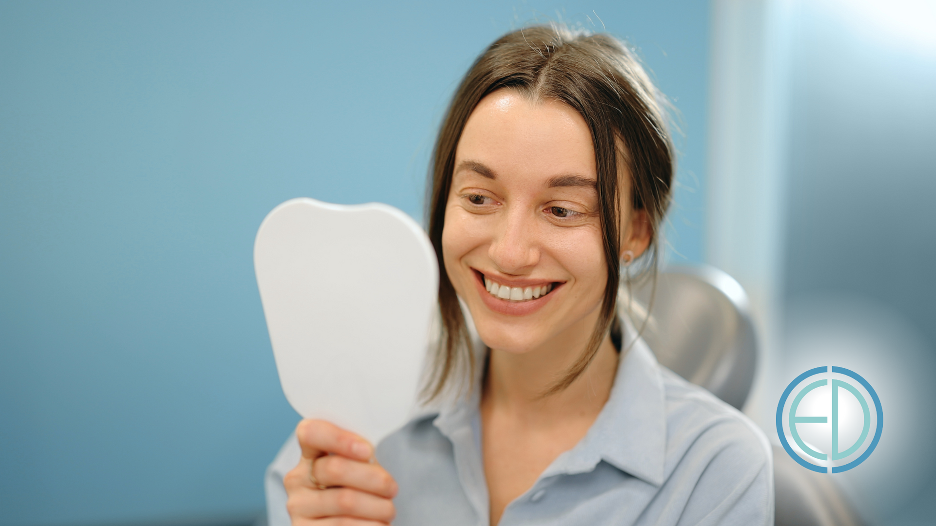 A woman is smiling while looking at her teeth in a mirror.