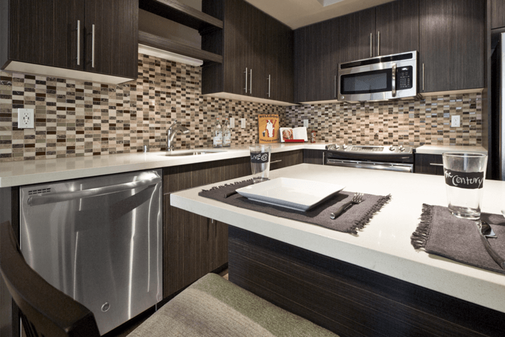 Interior view of a modern apartment kitchen with dark wood cabinets and stainless steel appliances.