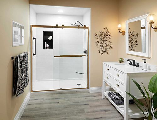 A bathroom with a sliding glass shower door , sink , mirror and plant.