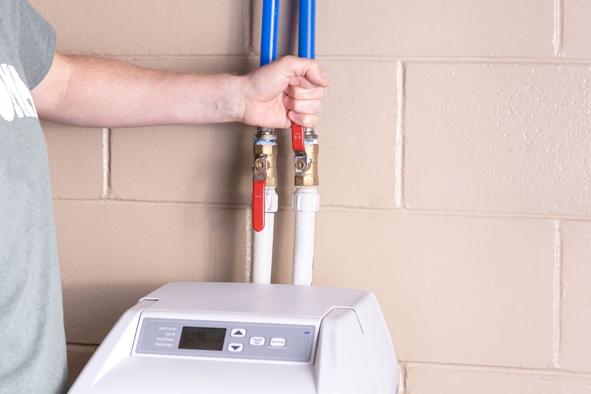Technician installing water softener with copper fittings and PEX lines.