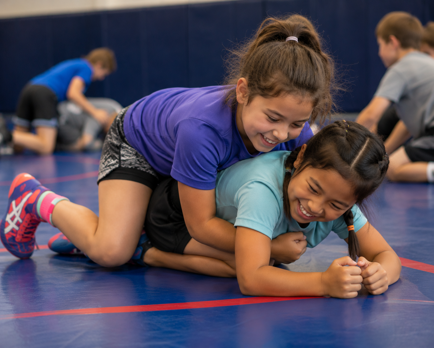 Two people grappling on a mat, one in a black gi, the other in a rash guard, legs entangled.