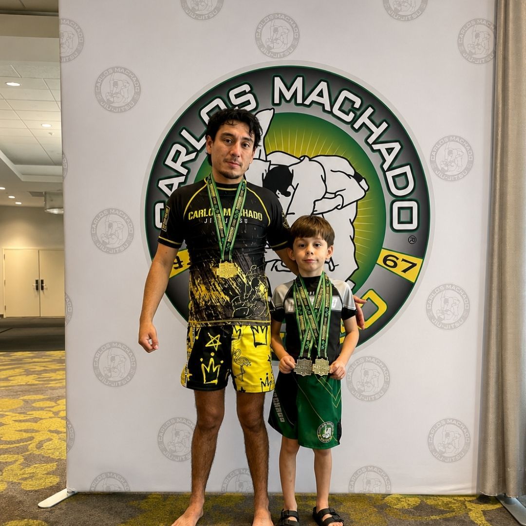 Two children grappling on a mat, one in a headlock.