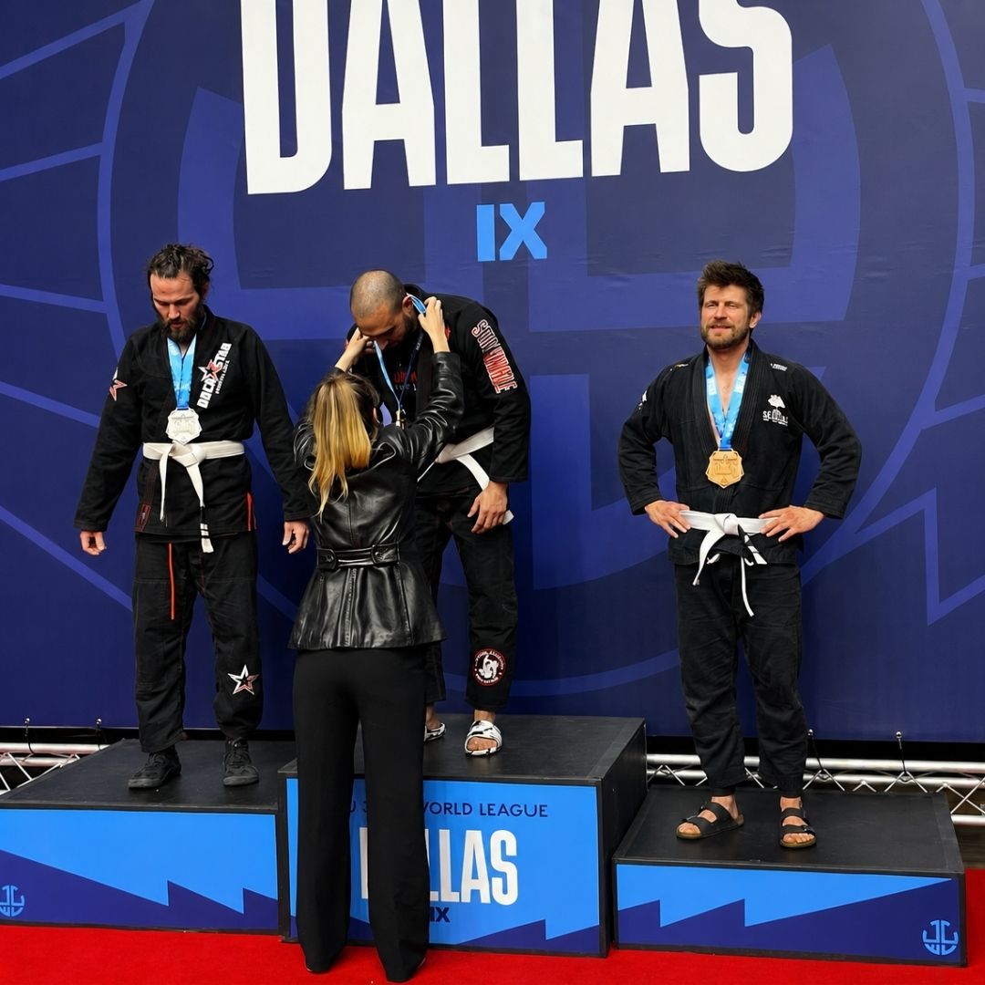 Two men grappling on a mat, one in blue, the other in black.
