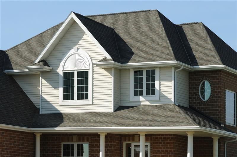 A large brick house with a gray roof and white siding